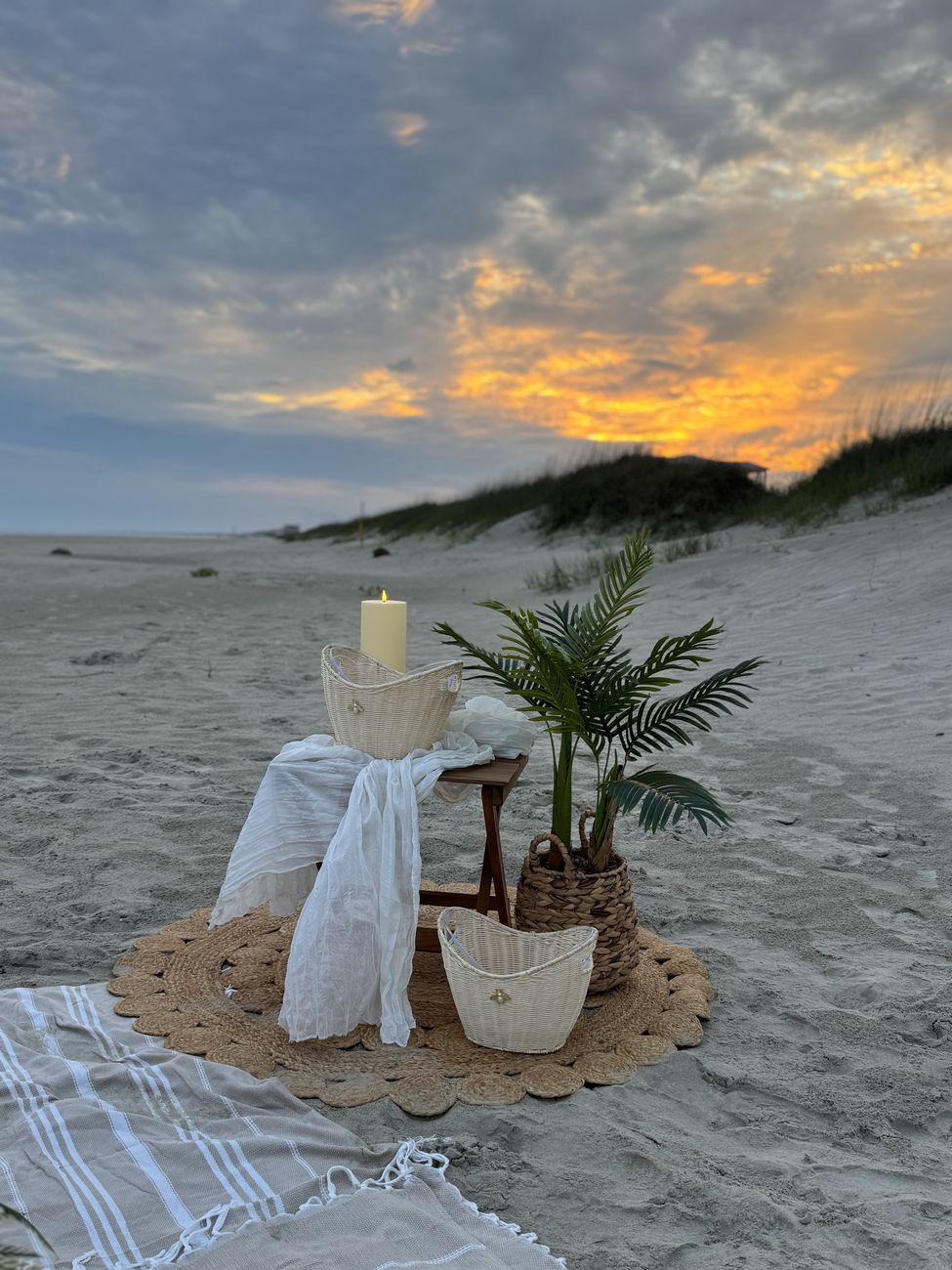 Candle and palm vignette on a jute mat at sunset
